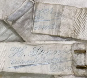 Label met tekst H. Spanier / Costumes & Confection / Deventer