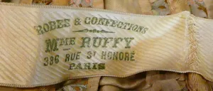 Label met tekst Robes & Confections / Mme Ruffy / 336 Rue St. Honoré / Paris