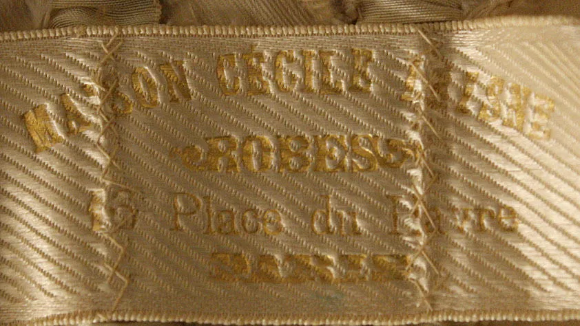 Label met tekst Maison Cécile Laisne / ROBES / 16 Place du Havre / PARIS