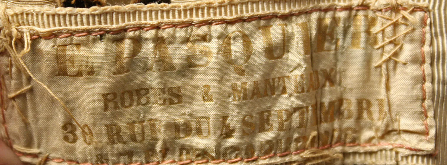 Label met tekst E. Pasquier / Robes et Manteaux / 30 Rue de 4 septembre / et 78 des Capucines