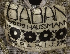 Label met tekst BABANI / 98 Bd HAUSSMANN / [ 4 fleurs stylisées ] / PARIS