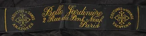 Label met tekst COSTUMES DE VOYAGE YATCHING [ A gauche en rond ] / Belle Jardinière 2, rue du Pont Neuf Paris / JAQUETTE DE DAMES AMAZONES [ A droite en rond et dessin ornemental au milieu ]